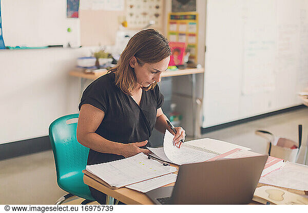 Elementary school teacher organizing papers in her classroom.