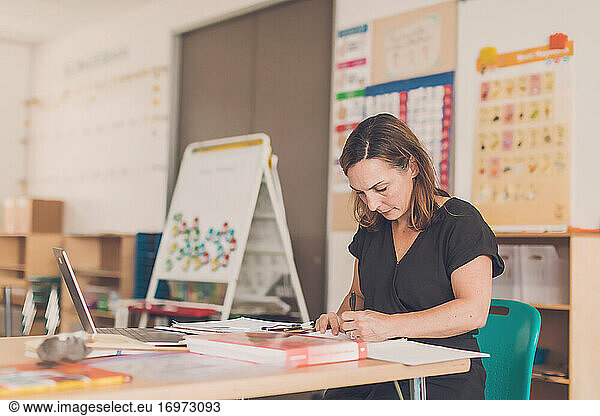 Elementary school teacher taking notes in her classroom.