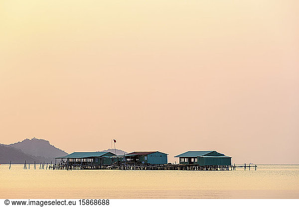 Elevated buildings on the water during a glowing pink sunset  Starfish Beach; Phu Quoc  Kien Giang Province  Vietnam