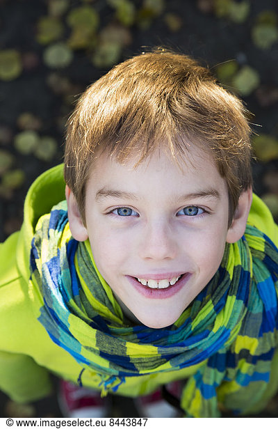 Elevated view of smiling young boy with hoodie jacket and scarf