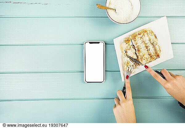 Elevated view woman s hand cutting lasagne