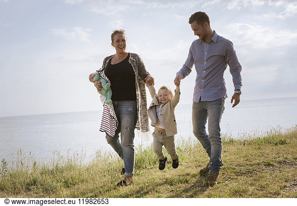 Eltern mit Söhnen (0-1 Monate  18-23 Monate) beim Spaziergang am Meer