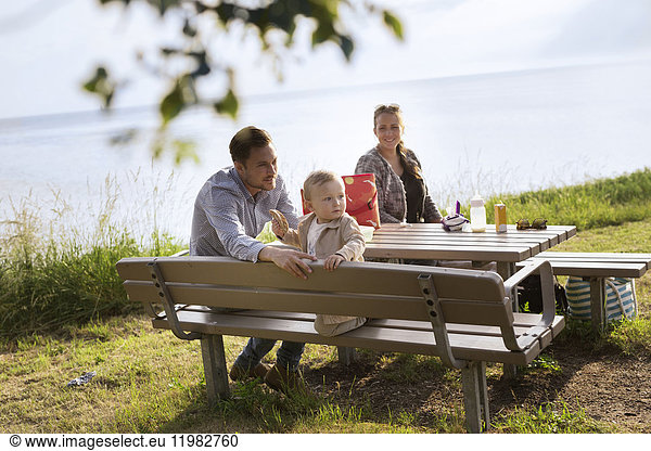 Eltern mit Sohn (18-23 Monate) sitzen am Picknicktisch