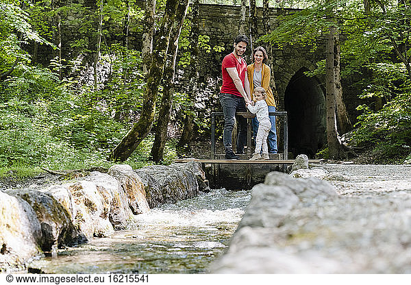 Eltern mit Tochter schauen auf den Staudamm  während sie im Wald stehen