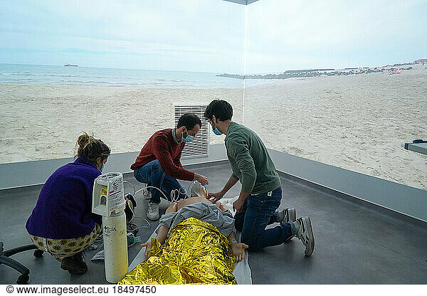 Emergency medicine students attends a circumstantial emergency simulation course led by two emergency physicians. Simulation of a drowning case at the beach. Realistic images and sound are projected all around the room to immerse students in total immersion. A young girl came up to the water's edge in cardiac arrest.
