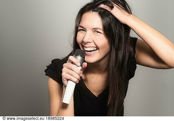 Emotional young woman singing her heart out into a microphone as she provides the vocals during a musical performance  karaoke or miming for her own entertainment