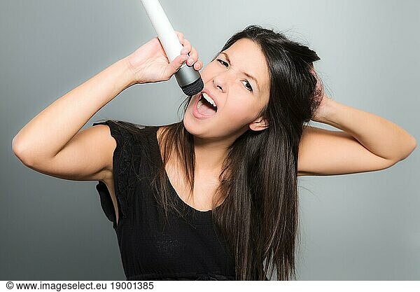 Emotional young woman singing her heart out into a microphone as she provides the vocals during a musical performance  karaoke or miming for her own entertainment