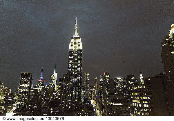 Empire State Building inmitten einer beleuchteten Stadt gegen den Himmel