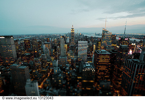 Empire State Building inmitten einer beleuchteten Stadtlandschaft in der Abenddämmerung