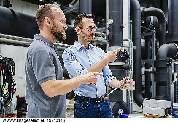 Employee and businessman with digital tablet talking in factory