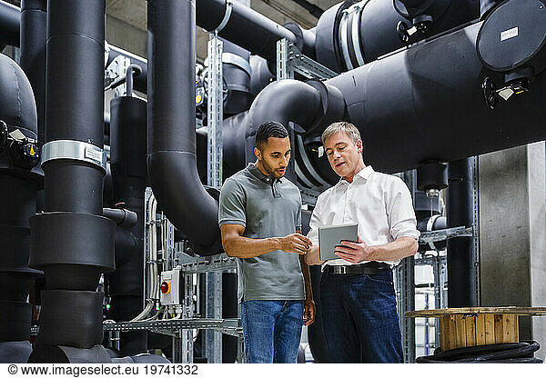 Employee and businessman with digital tablet talking in factory