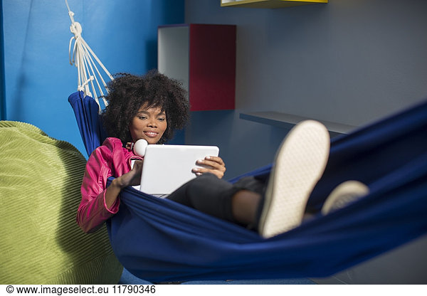 Employee with tablet relaxing in hammock