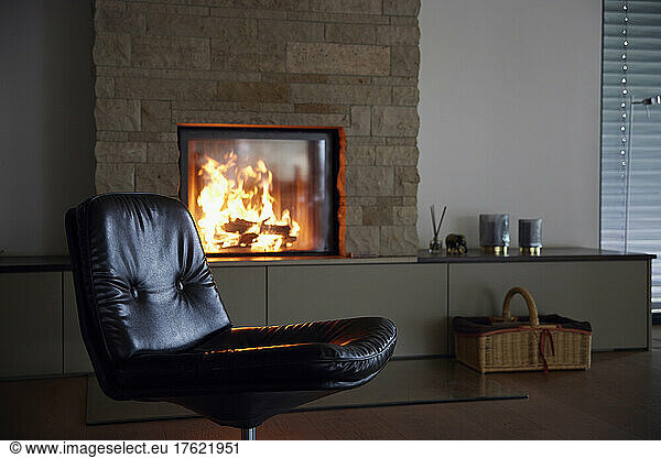 Empty black chair by fireplace at home