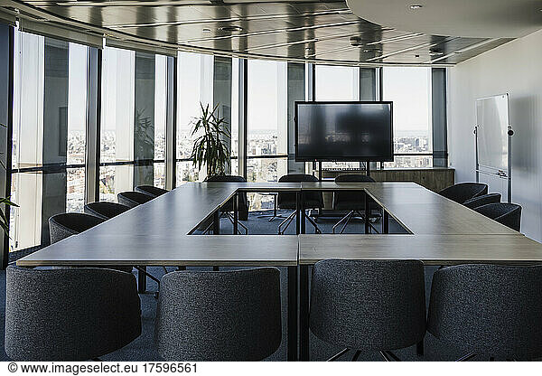 Empty board room with tables and chairs arranged in office