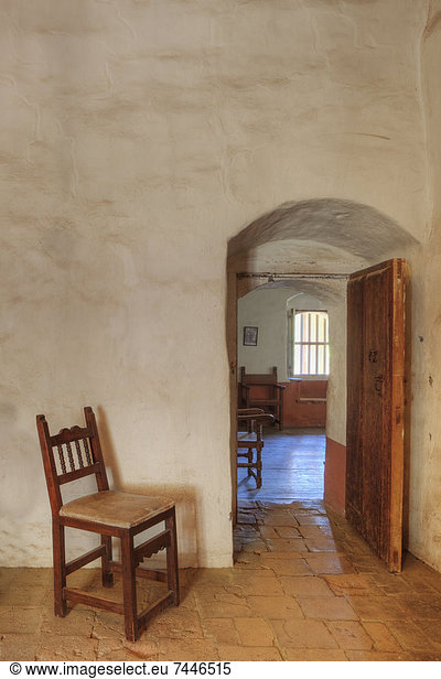Empty chair guards interior doorway of adobe building  Expecting company at Mission La Purisima State Historic Park  Lompoc  California  Founded in 1787  the eleventh mission of the twenty-one Spanish Missions established in California