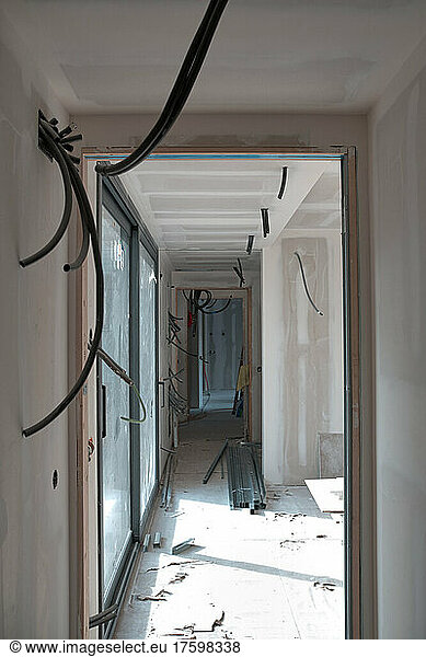 Empty corridor with cable wires seen through doorway at construction site