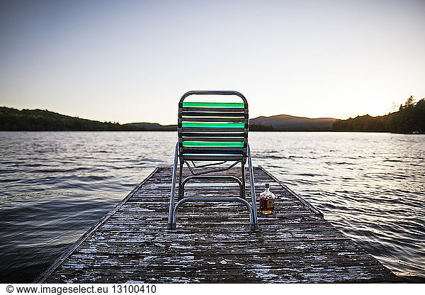 Empty deck chair on jetty by lake