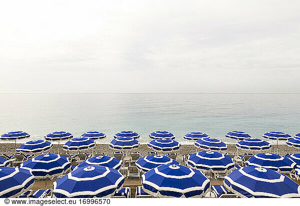Empty deck chairs and beach umbrellas along coastal beach of French Riviera