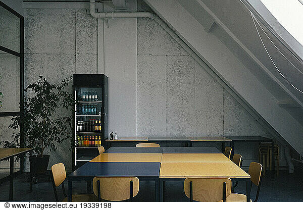 Empty dining table near refrigerator at office cafeteria