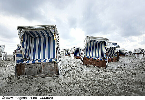 Empty hooded beach chairs on sandy beach