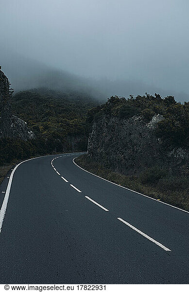 Empty long asphalt road in foggy weather