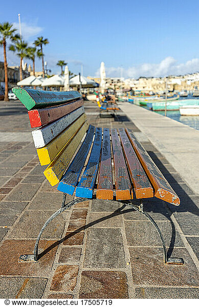 Empty multi colored bench overlooking city harbor