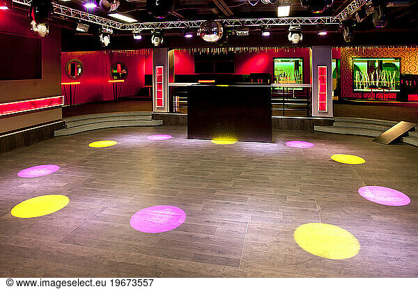 Empty nightclub  coloured lights and spots  screens and DJ decks.