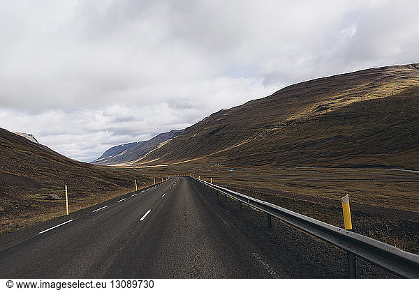 Empty road amidst mountains against cloudscape