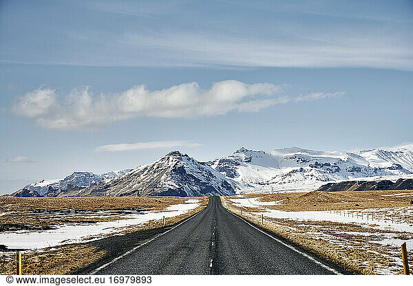 Empty road in terrain with snowy mountains