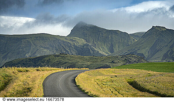 Empty road leading towards mountains in South Iceland against sk