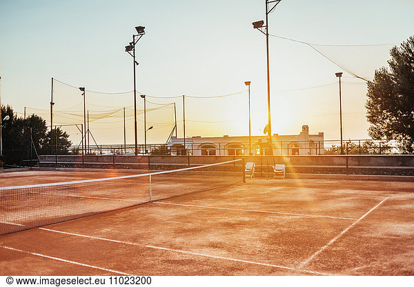 Empty tennis court against sky during sunset