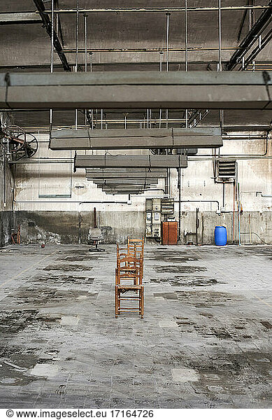 Empty wooden chairs in abandoned factory