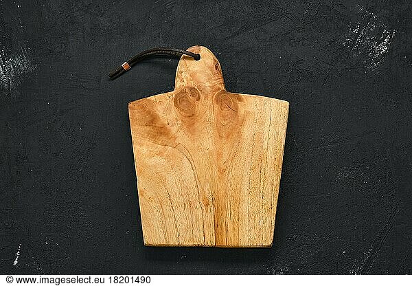 Empty wooden cutting board on black shabby background