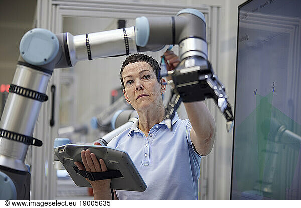 Engineer checking robotic arm holding equipment in industry