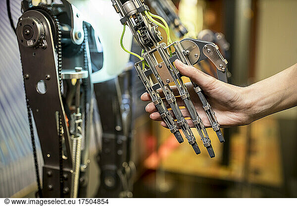 Engineer doing handshake with robotic arm at workshop