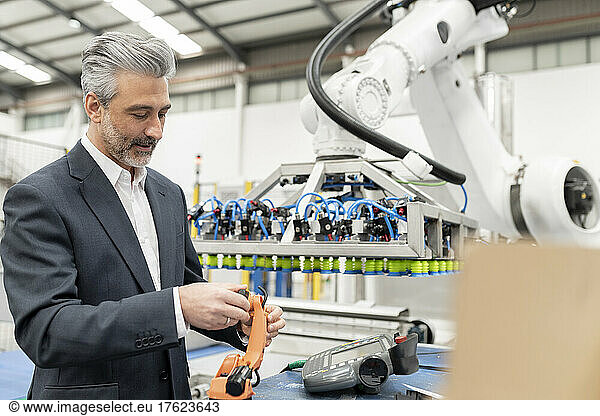 Engineer examining robotic arm model in factory