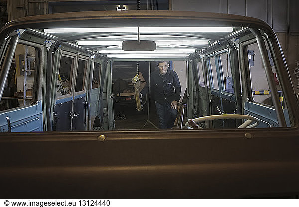 Engineer examining van in automobile factory seen through windshield