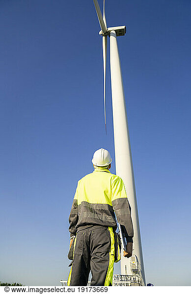 Engineer examining wind turbine on sunny day