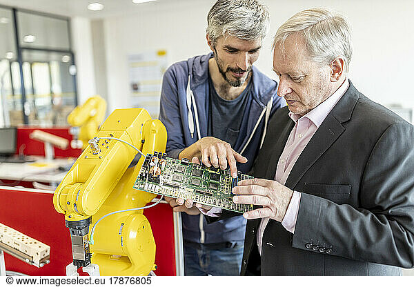 Engineer explaining new robot motherboard to supervisor