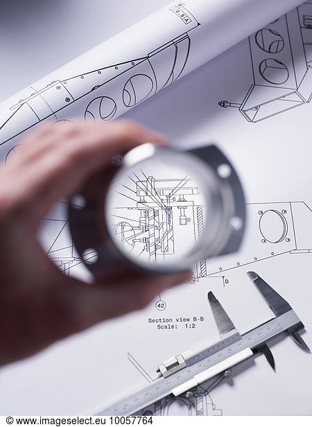 Engineer holding a precision made component over a technical drawing with a dial caliper