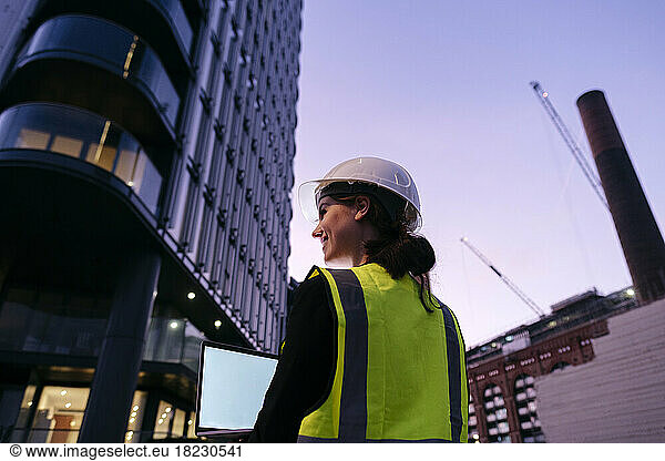 Engineer holding laptop at dusk