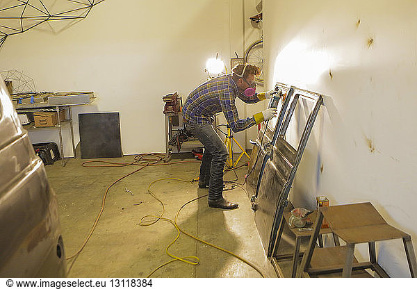 Engineer polishing van doors with angle grinder in factory