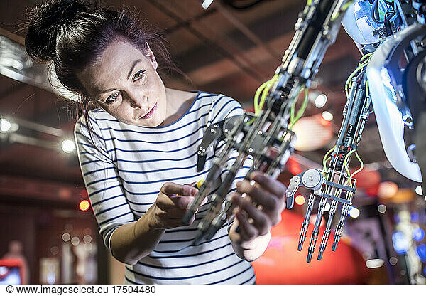 Engineer repairing robotic arm in workshop