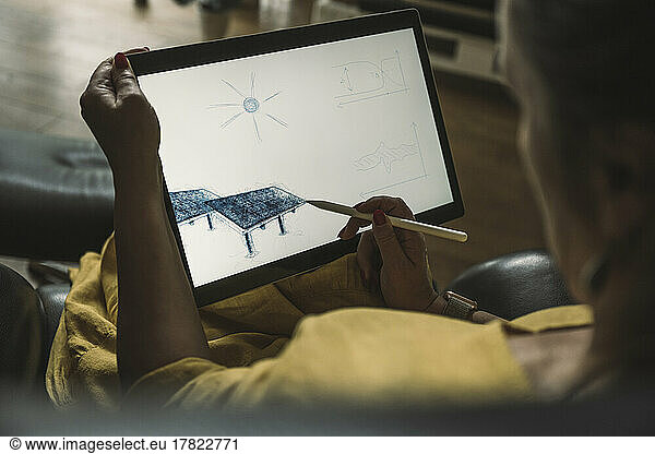 Engineer sketching solar panel on graphics tablet at home office