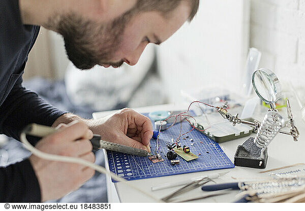 Engineer soldering circuit board at workshop