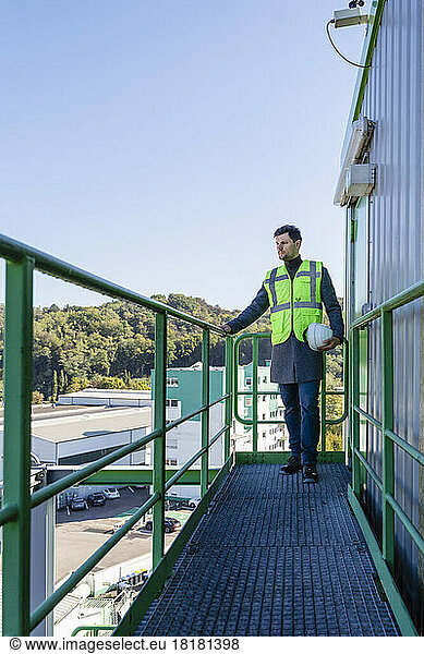 Engineer standing by railing at industrial plant