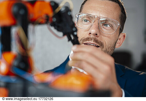 Engineer wearing eyeglasses looking at robotic model