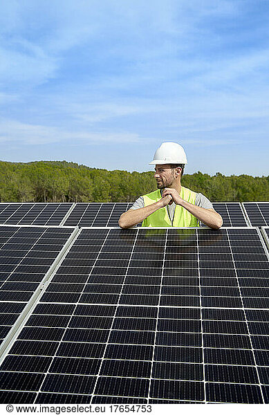 Engineer wearing hardhat between solar panels on roof