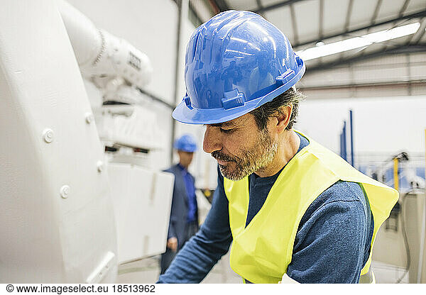Engineer wearing hardhat working on robotic arm