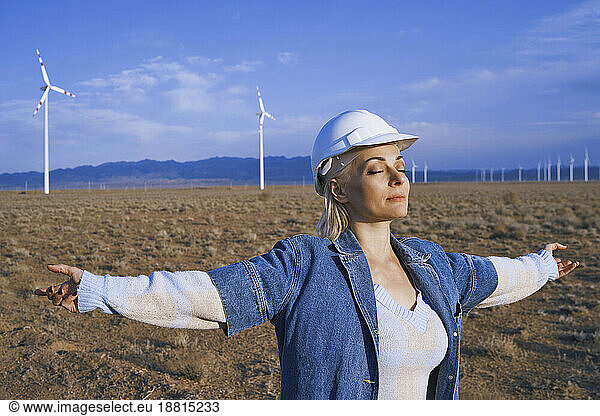 Engineer with arms outstretched and eyes closed standing in desert